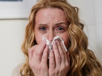 woman sick with cold covering her nose